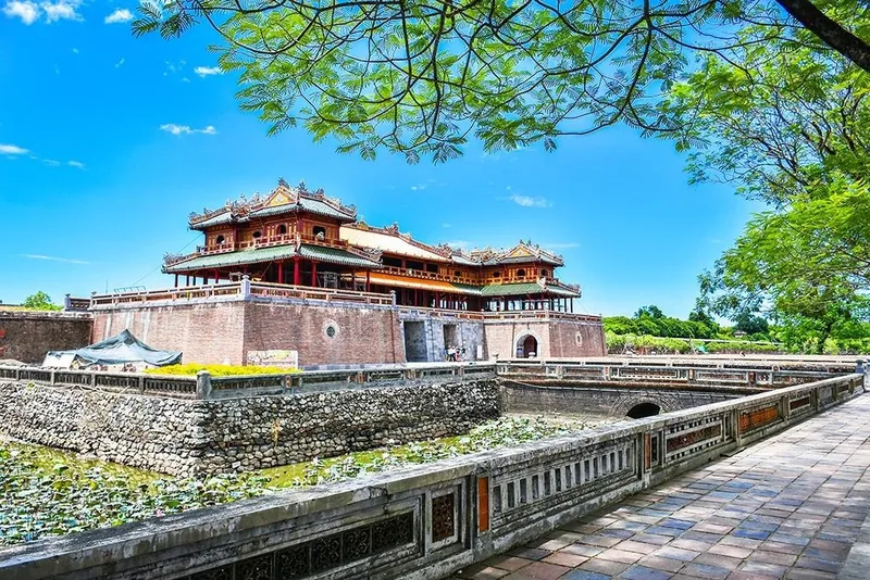 The Meridian Gate of Hue Imperial Citadel stands beside a moat under a bright blue sky.