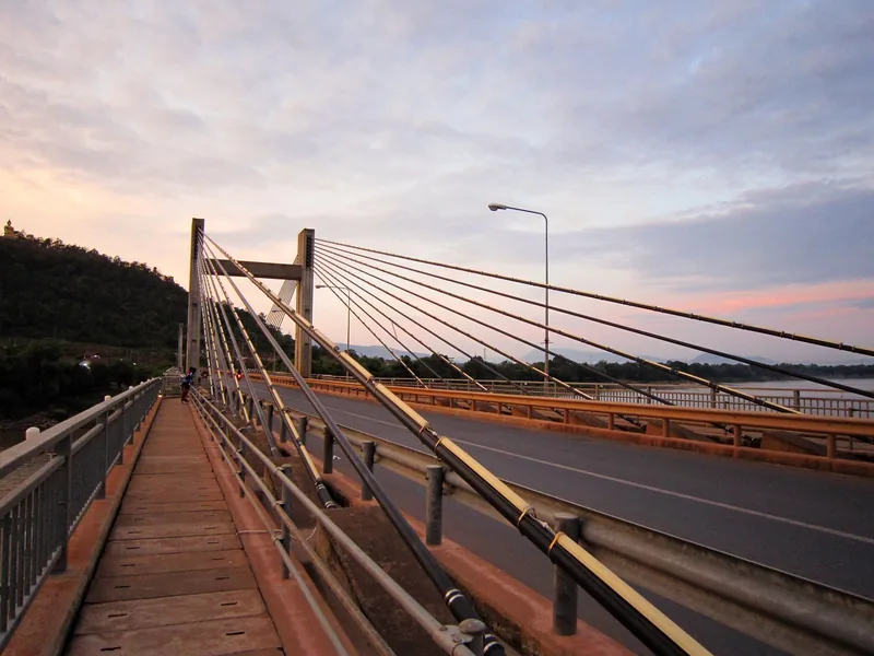 A cable-stayed bridge crosses the river near Pakse under a soft evening sky.